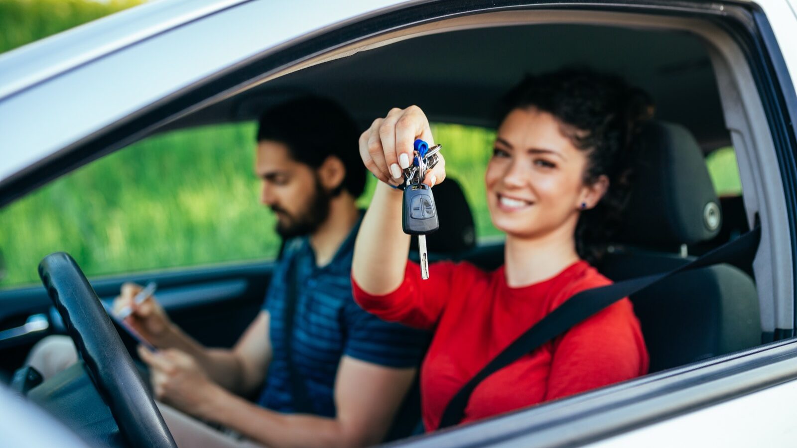 A driving instructor sitting beside a learner at the wheel.
