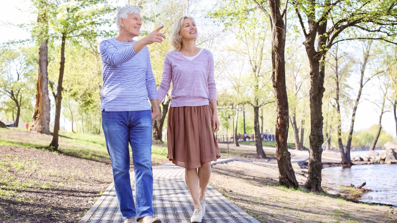 An older couple walking together along a park path.