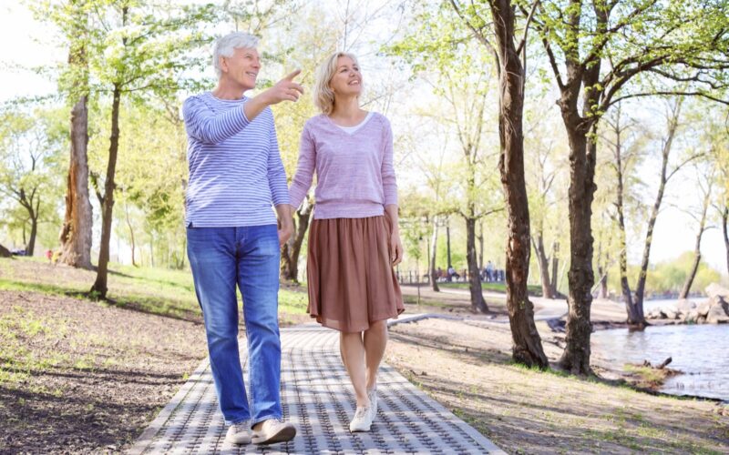 An older couple walking together along a park path.