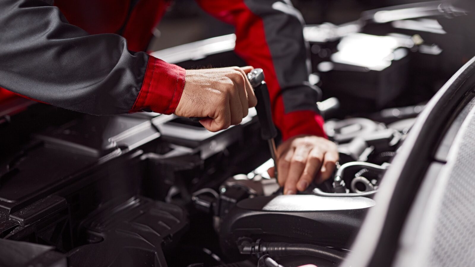 A mechanic working on a car engine in a workshop.