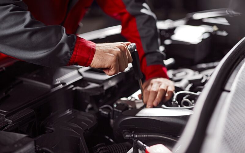 A mechanic working on a car engine in a workshop.