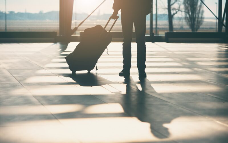 A traveler’s shadow cast across an airport terminal floor.