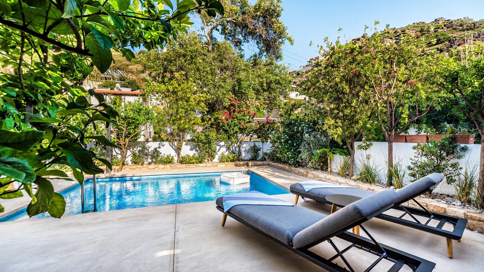 A private swimming pool and terrace beside a house.