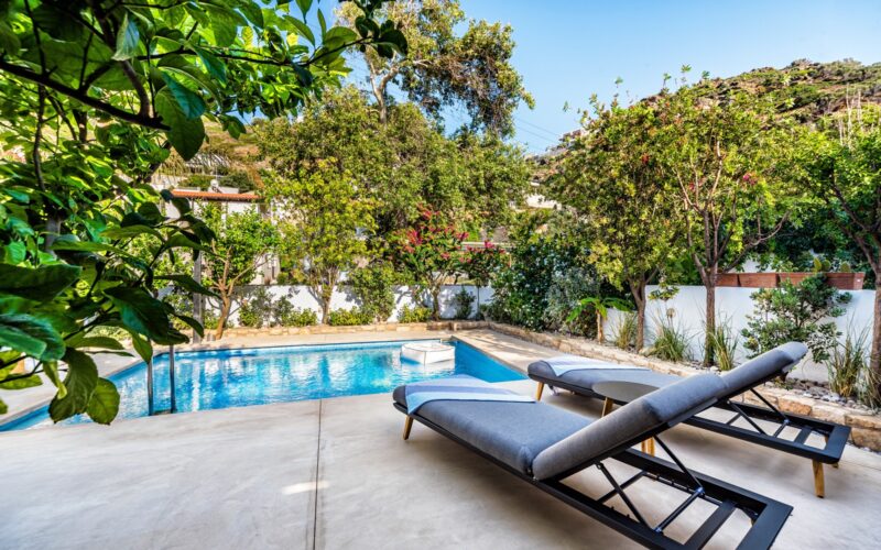 A private swimming pool and terrace beside a house.